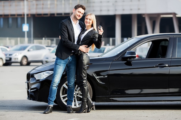 Happy young couple chooses and buying a new car for the family