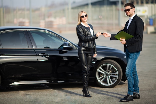 Happy young couple chooses and buying a new car for the family.