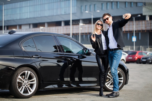 幸せな若いカップルは、家族のために新しい車を選んで購入します。