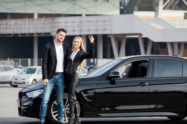 Happy young couple chooses and buying a new car for the family.