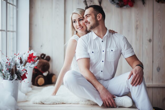 Happy young couple at christmas, beautiful gifts and tree in the 