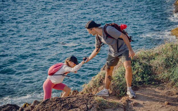 写真 幸せな若いカップルが海の近くの山の頂上に登ります