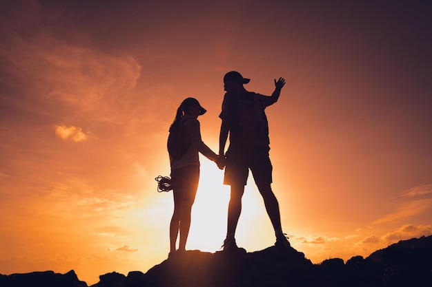 Happy young couple climbs to the top in the mountains near the ocean