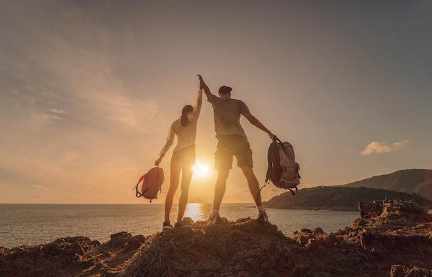 Happy young couple climbs to the top in the mountains near the ocean