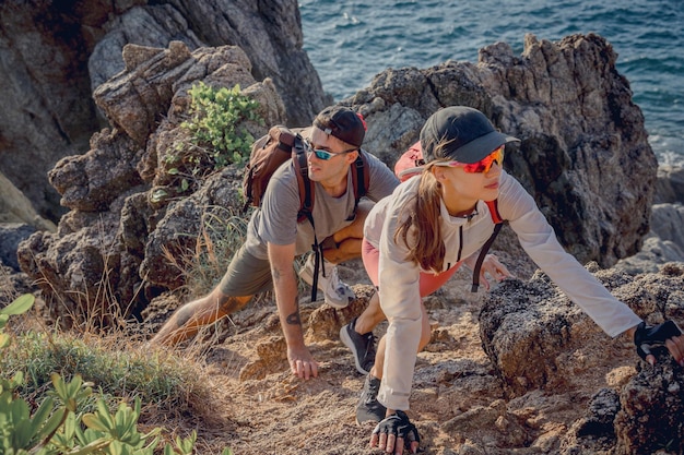 Happy young couple climbs to the top in the mountains near the ocean