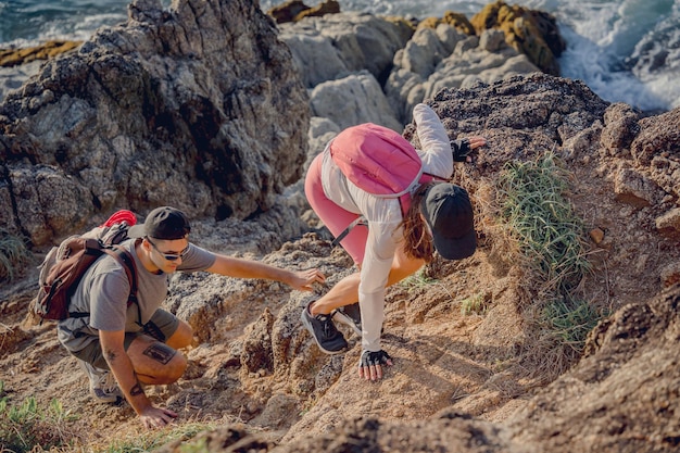 Happy young couple climbs to the top in the mountains near the ocean