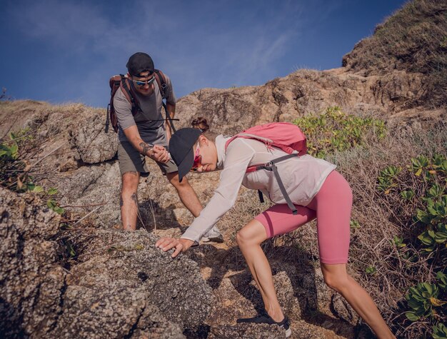 happy young couple climbs to the top in the mountains near the ocean