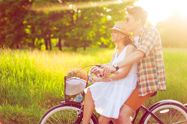 Happy young couple cycling through the park