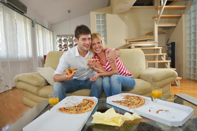 happy young couple eat fresh pizza at home relaxing and watch tv