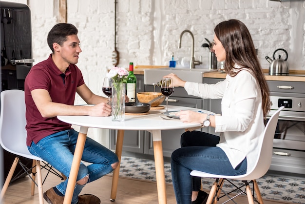 Happy young couple eating and drinking wine at home