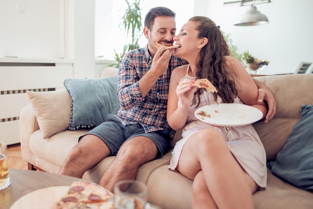 happy young couple eating pizza in the living room