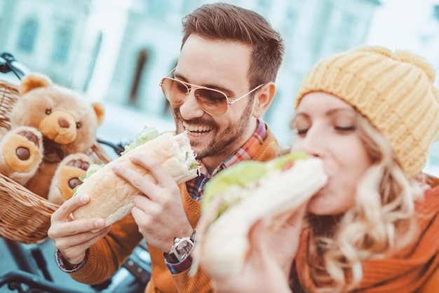 Happy young couple eating sandwich