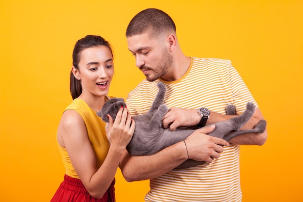 Giovani coppie felici che si godono il tempo con il loro gatto. uomo bello che tiene adorabile gatto.