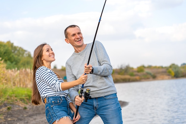 Happy young couple fishing by lakeside