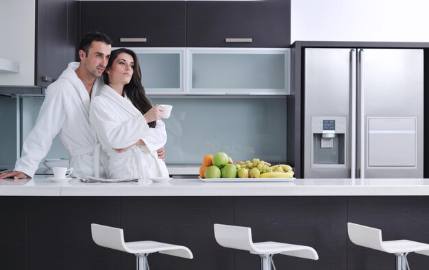 счастливая молодая пара развлекается на современной кухне в помещении, готовя салат из свежих фруктов и овощей