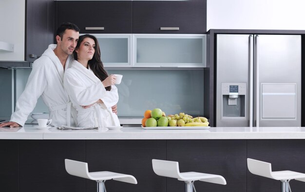 happy young couple have fun in  modern kitchen indoor  while preparing fresh fruits and vegetables food salad