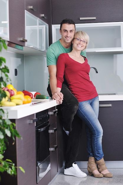 happy young couple have fun in  modern kitchen indoor  while preparing fresh fruits and vegetables food salad