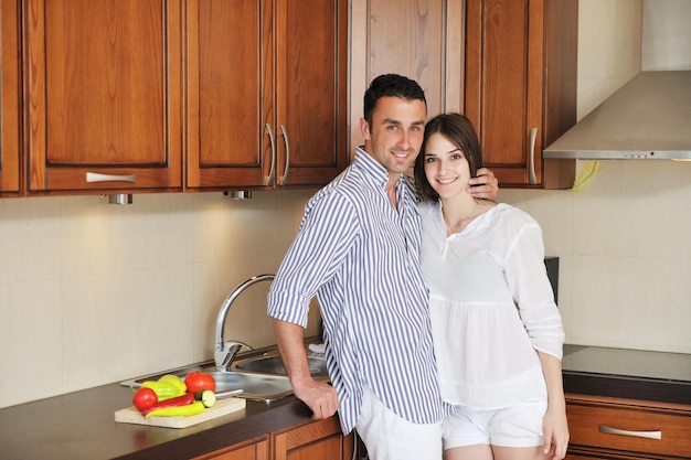 행복한 젊은 커플은 신선한 음식을 준비하는 동안 실내 현대적인 목조 주방에서 즐거운 시간을 보냅니다.