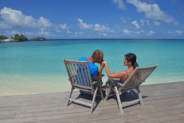 행복한 젊은 부부는 배경 몰디브 여행지와 아름다운 하얀 모래 해변에서 여름 휴가를 즐기고 휴식을 취합니다.
