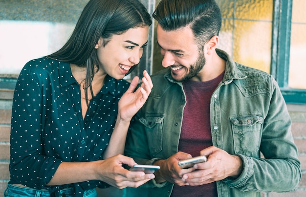 Happy young couple having fun with mobile smart phone at urban place