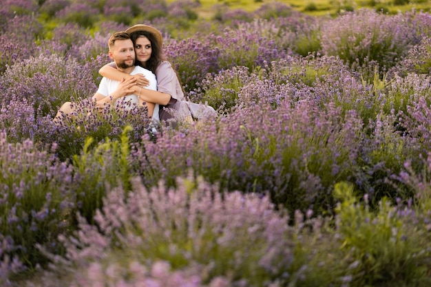 Happy young couple having a romantic date at the lavender field sitting and hugging