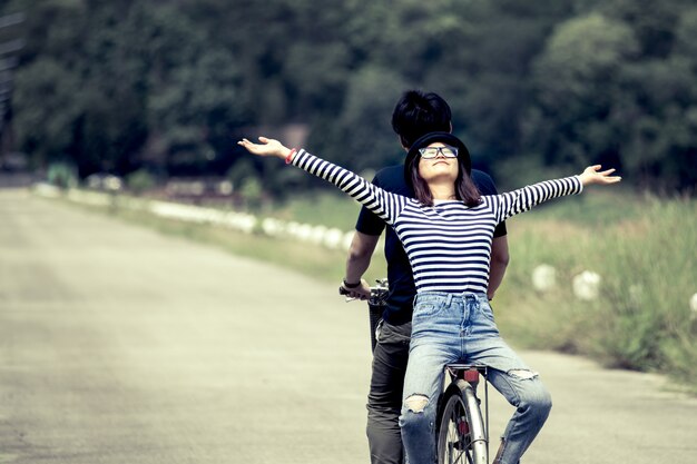 Happy young couple of hipsters riding a bicycle together in vintage color tone