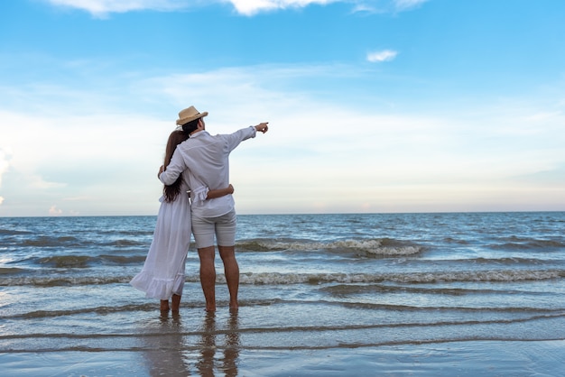 Foto giovani coppie felici che si tengono e che ridono con godendo insieme sulla spiaggia di estate.