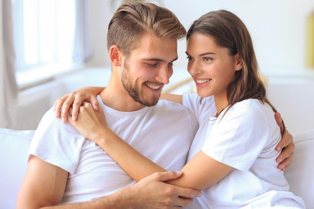 Happy young couple hugging and looking at each other at home interior