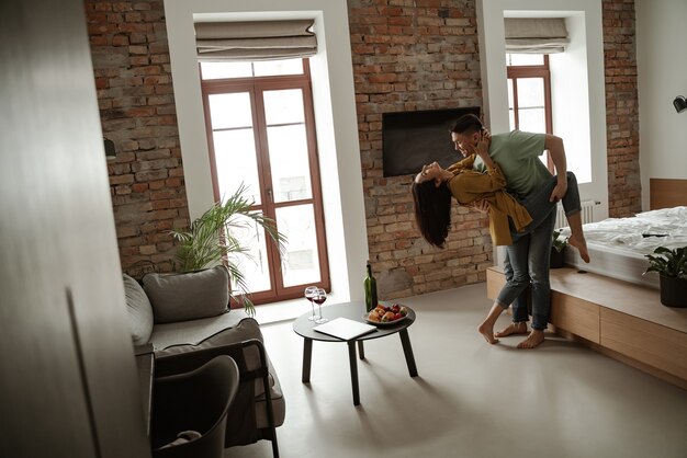 Photo happy young couple is dancing and showing their feelings in new flat. lovely family moving to new apartment.