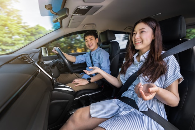 幸せな若いカップルが車を運転しながら話している