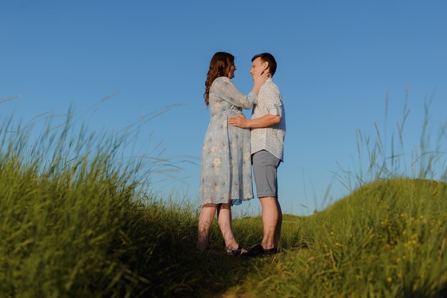 澄んだ空と山の頂上でキスする幸せな若いカップル。幸せな家族