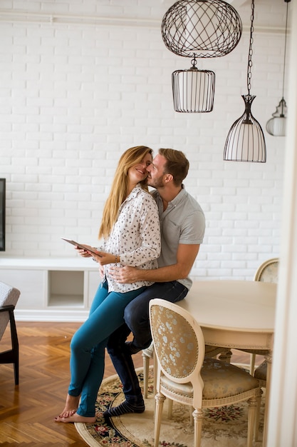 Photo happy young couple looking at digital tablet in living room