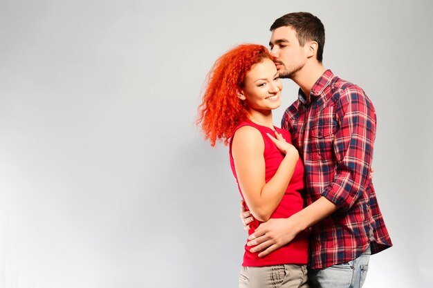 Happy young couple in love embracing on grey background