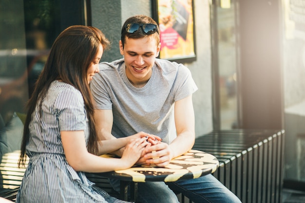 Happy young couple in love teenagers friends dressed in casual style sitting together 