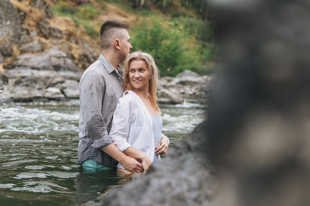 Happy young couple in love travelers kissing in the mountain river