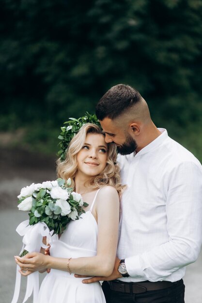 Photo a happy young couple in love walk in a garden a man in a white shirt and a girl in a white light dress are walking in a park