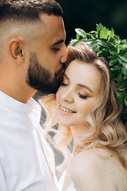 A happy young couple in love walk in a garden A man in a white shirt and a girl in a white light dress are walking in a park