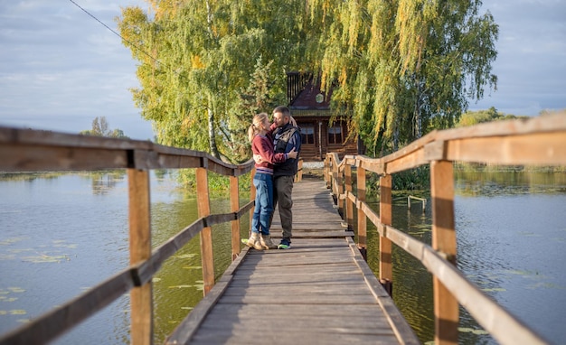 Счастливая молодая влюбленная пара гуляет по мосту на закате Мужчина обнимает и собирается поцеловать чувственную женщину
