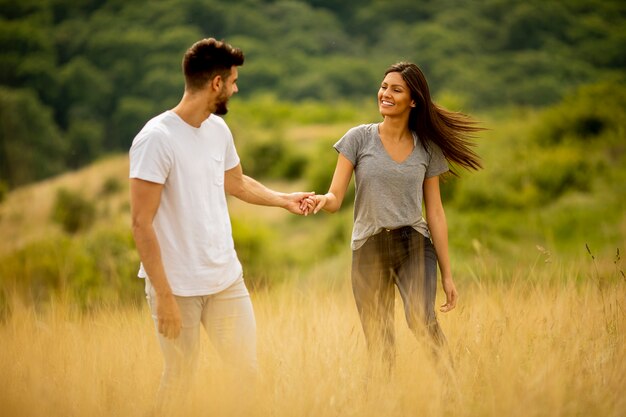 Счастливая молодая влюбленная пара гуляет по траве в летний день