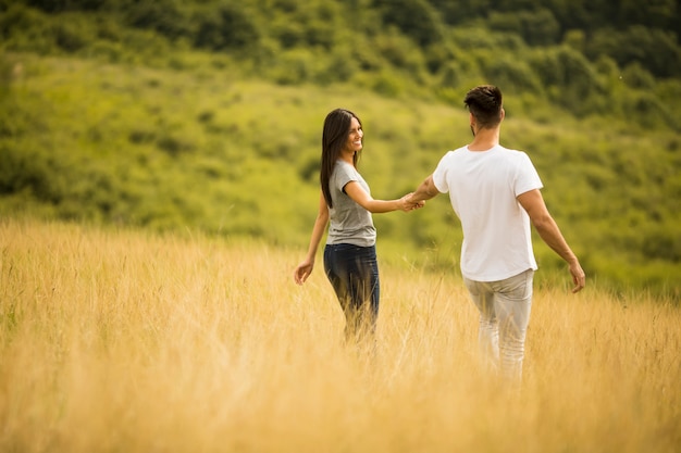 Giovani coppie felici nell'amore che cammina attraverso il campo di erba