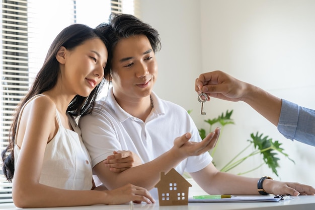 Photo happy young couple man and woman getting the new home keys from the real estate agent