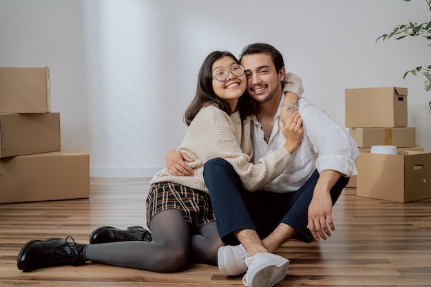 Happy young couple moves into their first apartment together the couple sits embracing each other