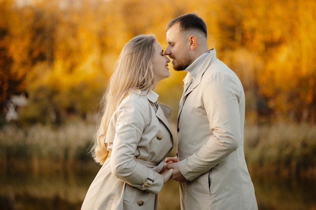 Happy young couple outdoors on a sunny autumn day, couple in autumn park are kissing.