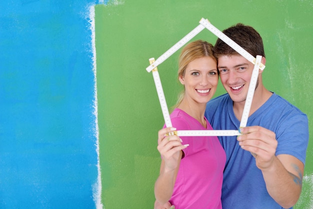 Felice coppia giovane dipingere in colore verde e blu muro bianco della loro nuova casa