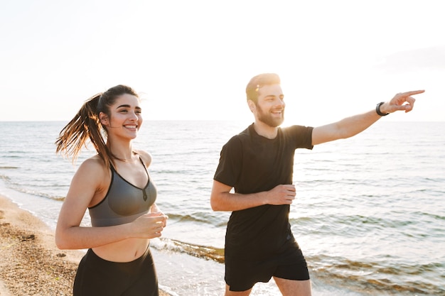 Happy young couple pointing away while jogging