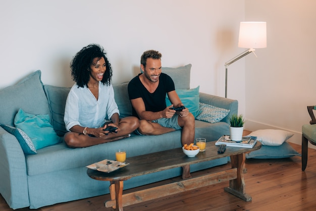 Happy young couple relaxed at home in the couch having fun playing video games