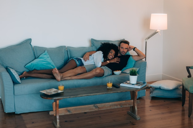 Foto le giovani coppie felici si sono rilassate a casa nello strato divertendosi guardando la tv