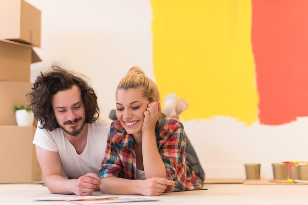 Happy young couple relaxing after painting a room in their new house on the floor