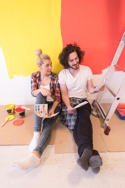 Photo happy young couple relaxing after painting a room in their new house on the floor