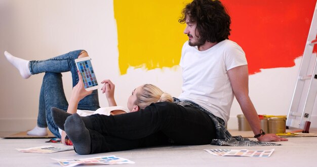 Happy young couple relaxing after painting a room in their new house on the floor